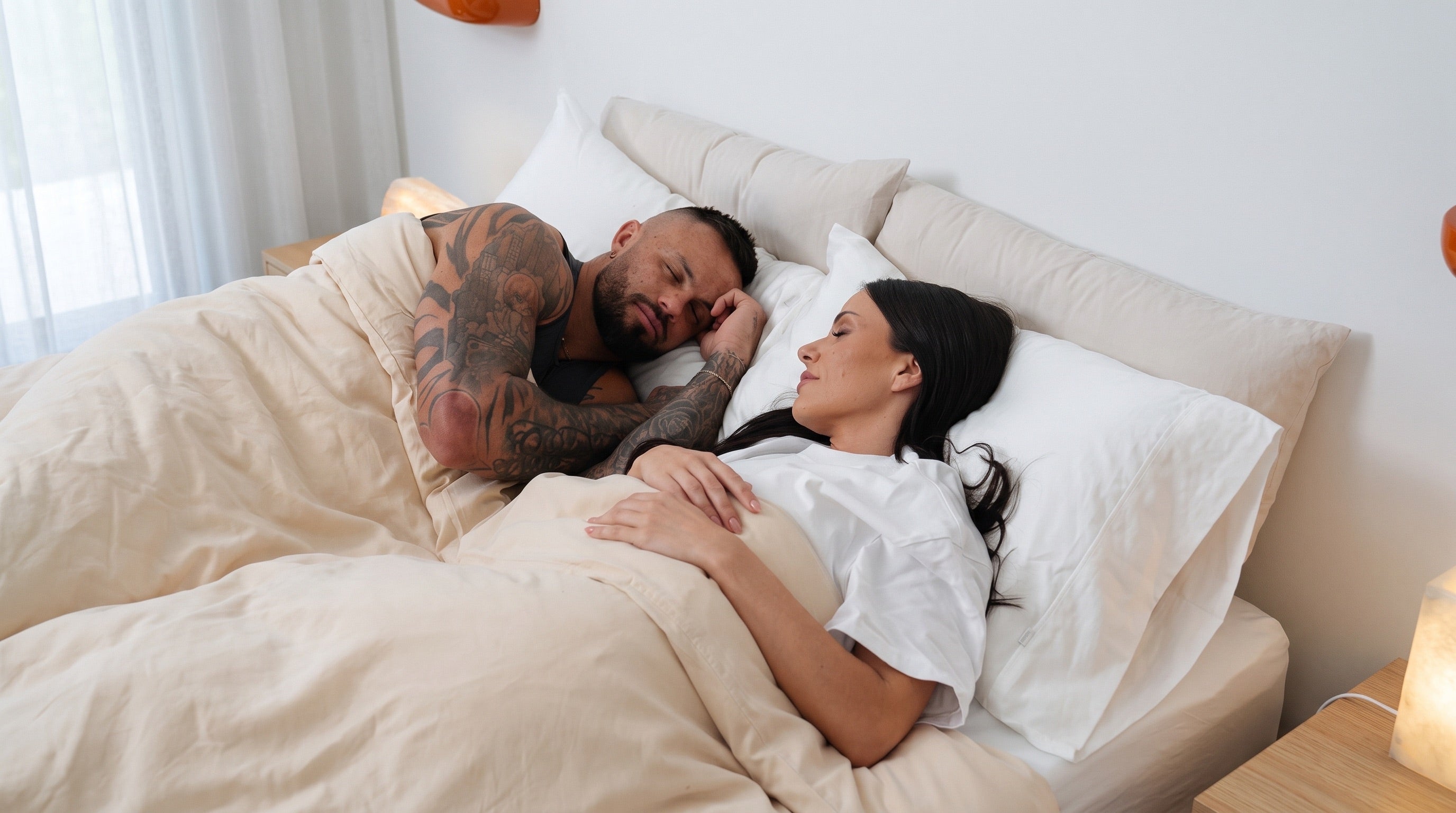 Two adults resting beneath cream bedding